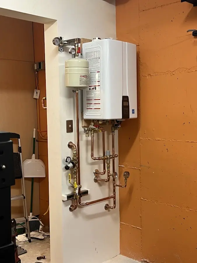 Plumbing technician inspecting water heater connections in Conewango